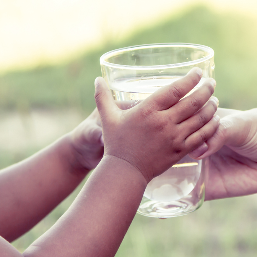 two people holding a glass of water